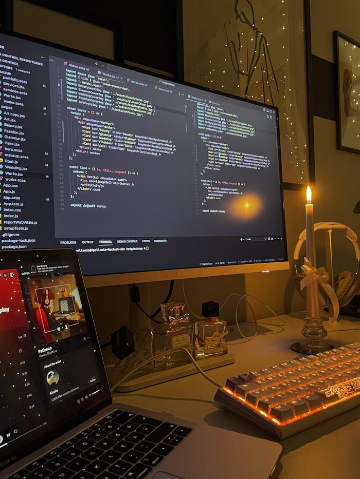about-02 A tech workspace featuring a lit candle and a computer screen displaying code, creating a warm coding environment.